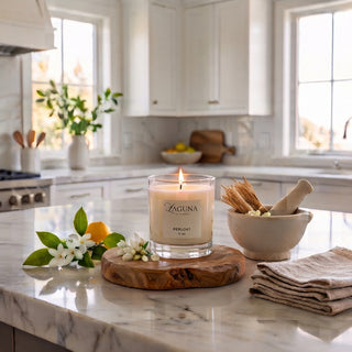 Panel 1: Lit Laguna “PERLOAT” candle on a marble countertop with fresh lemons and white blossoms.
