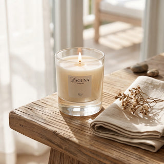 Panel 1: Lit Laguna “821-A” candle on a wooden table with a folded cream cloth and a small dried floral stem.