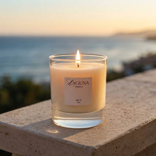 Panel 1: Lit Laguna “821-A” candle glowing warmly on an outdoor ledge against an evening sunset and ocean background.